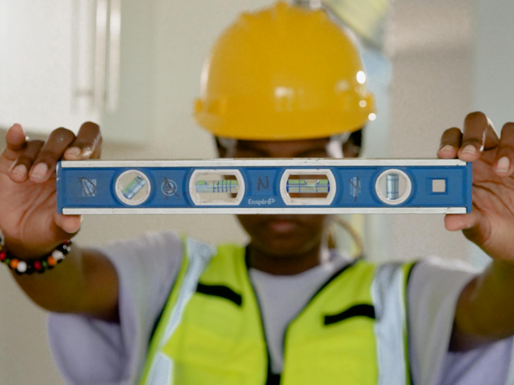 Pracownik budowlany w pomieszczeniu sprawdza poziomicą pionowość powierzchni