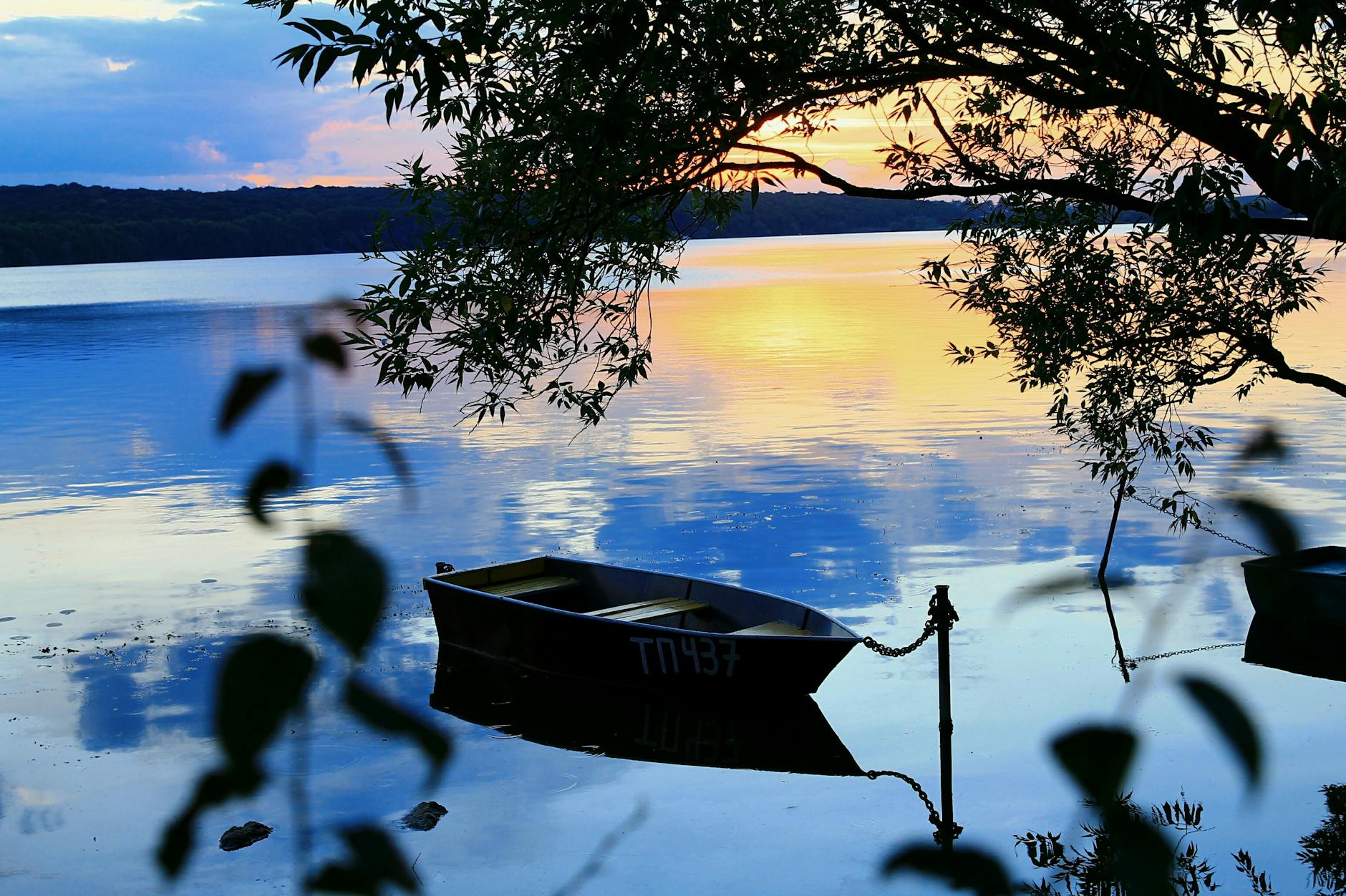 Romantyczne rejsy o zachodzie słońca w Austrii: najlepsze jeziora i przystanie dla par Łódź zacumowana na austriackim jeziorze o zachodzie słońca