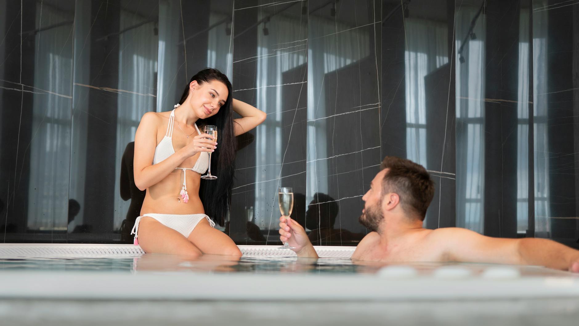 Para w jacuzzi z kieliszkami szampana podczas romantycznego weekendu