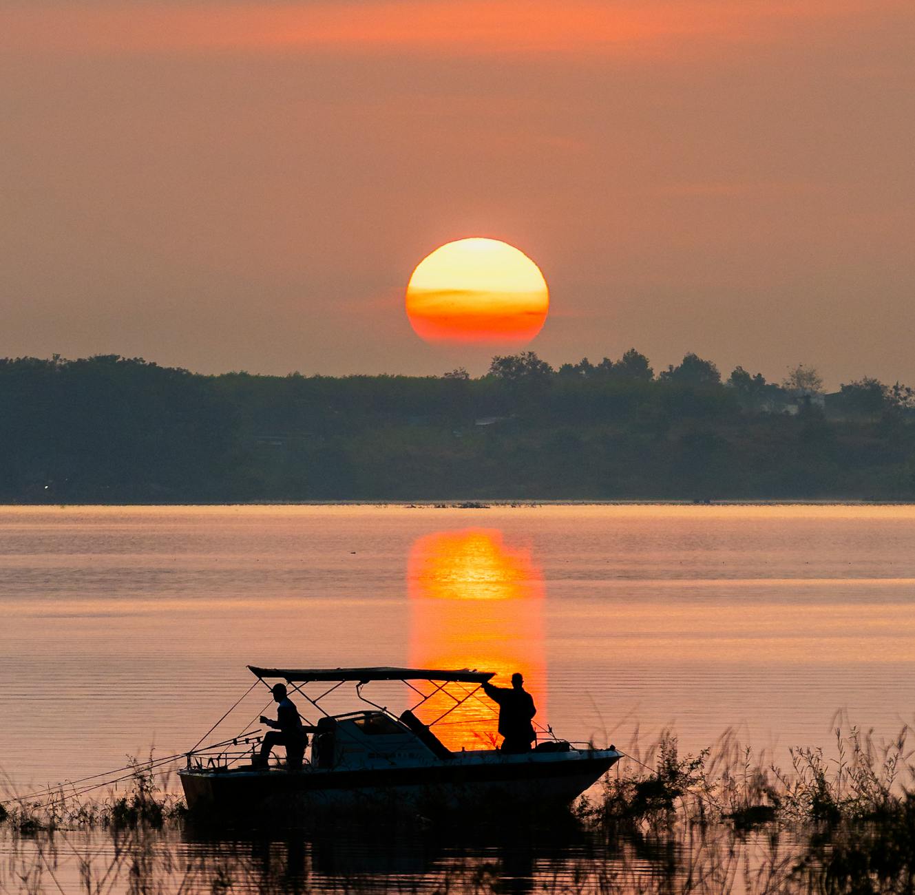 Sylwetka łodzi o zachodzie słońca na spokojnym austriackim jeziorze
