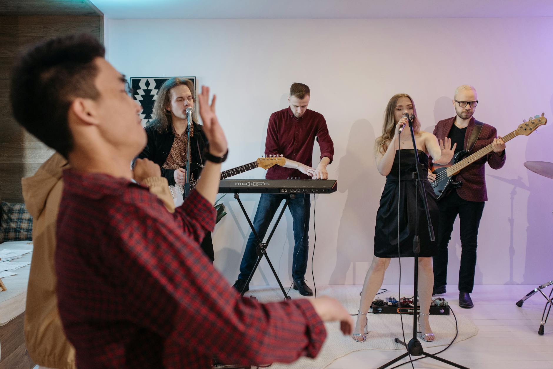 Zespół muzyczny gra na scenie w sali pełnej bawiących się gości