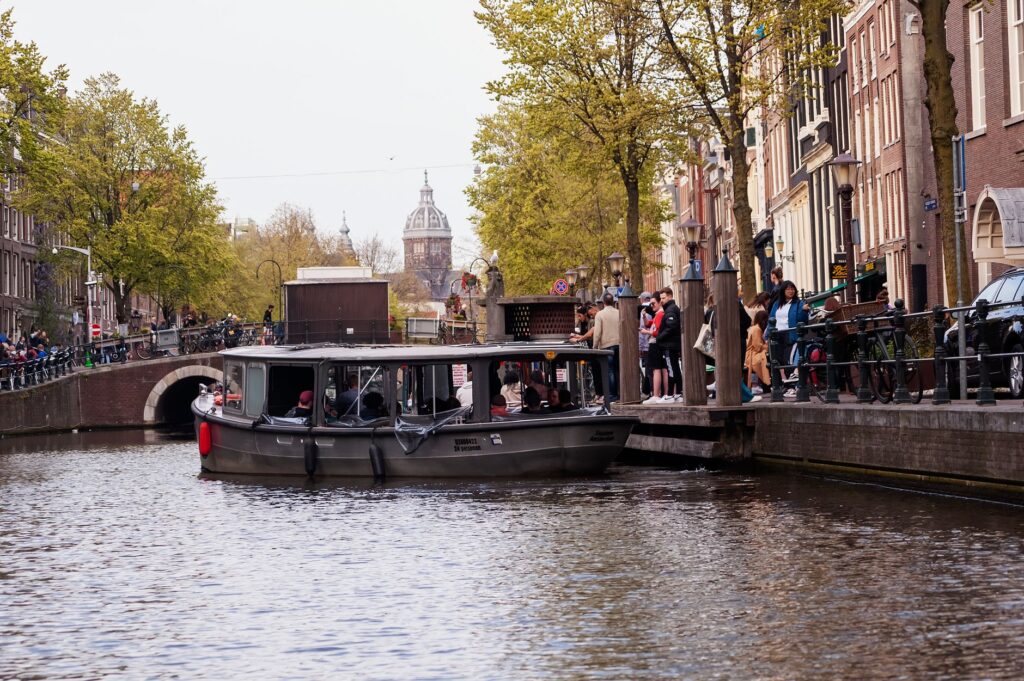 Łódź płynąca kanałem w Amsterdamie przy zabytkowym moście